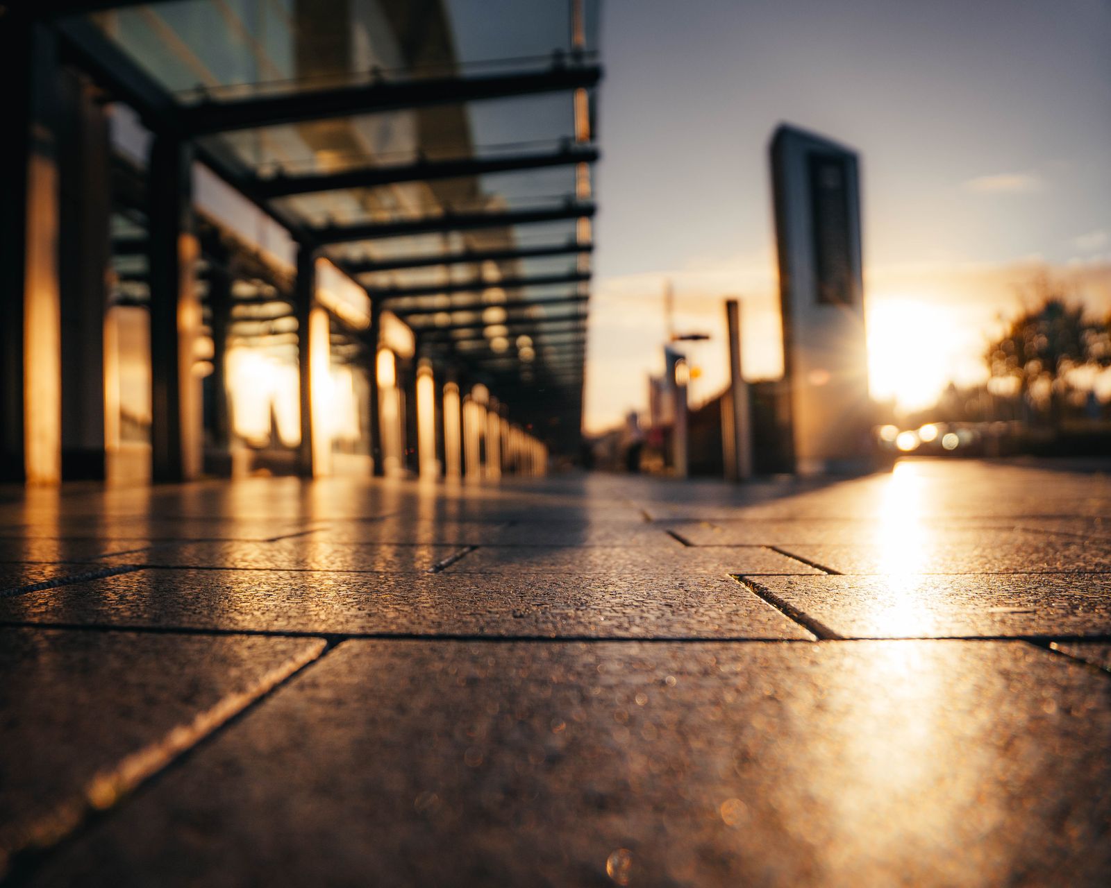 Low sun raking across paving stones under a covered walkway.