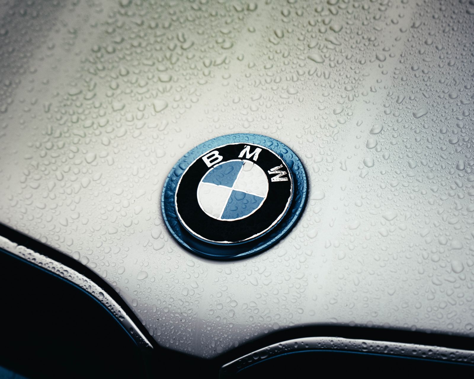 The BMW roundel on the bonnet, covered in raindrops.
