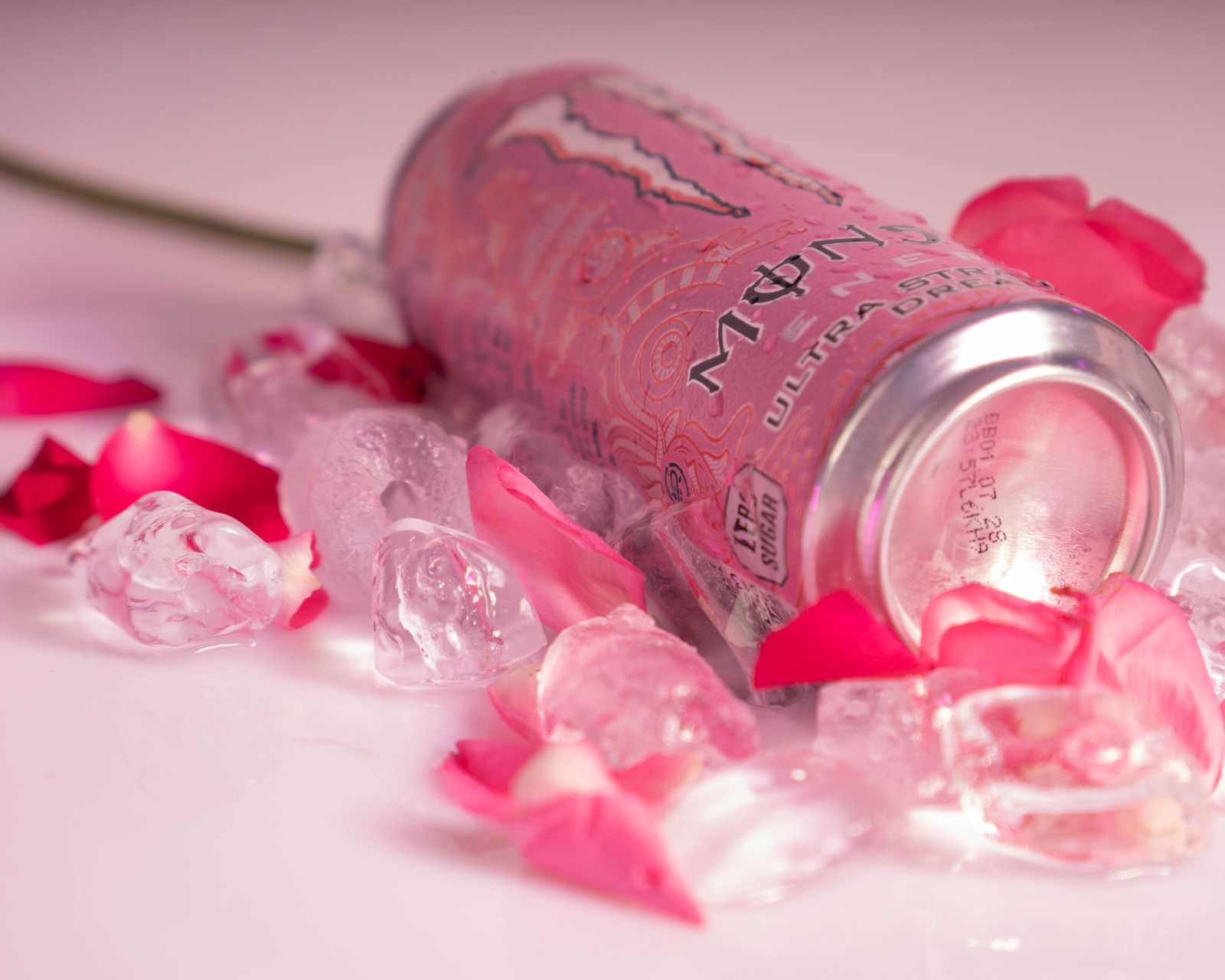 The can on its side, label up, with petals and a rose stem.