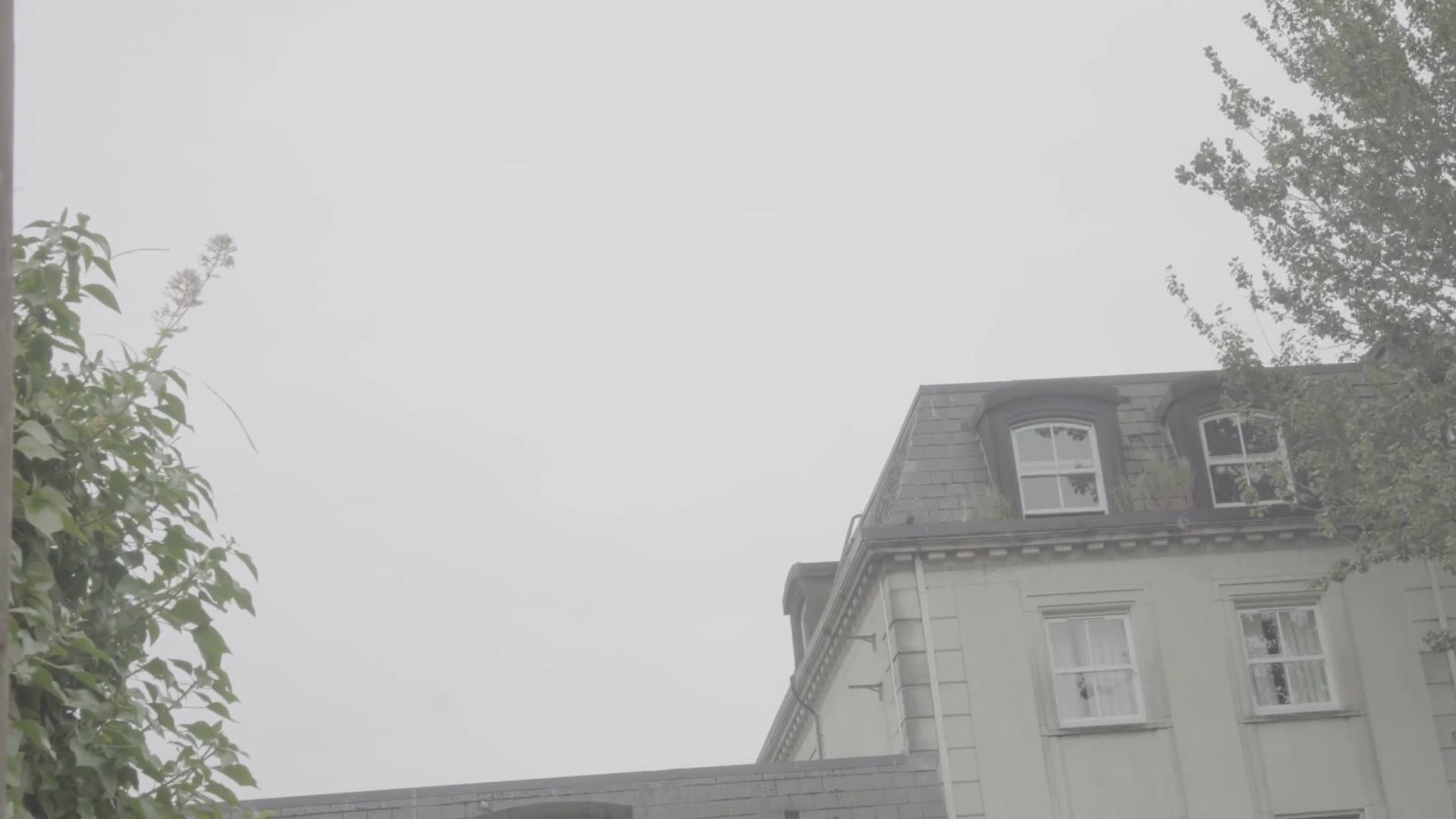 The original plate: a plain building and grey sky before compositing.